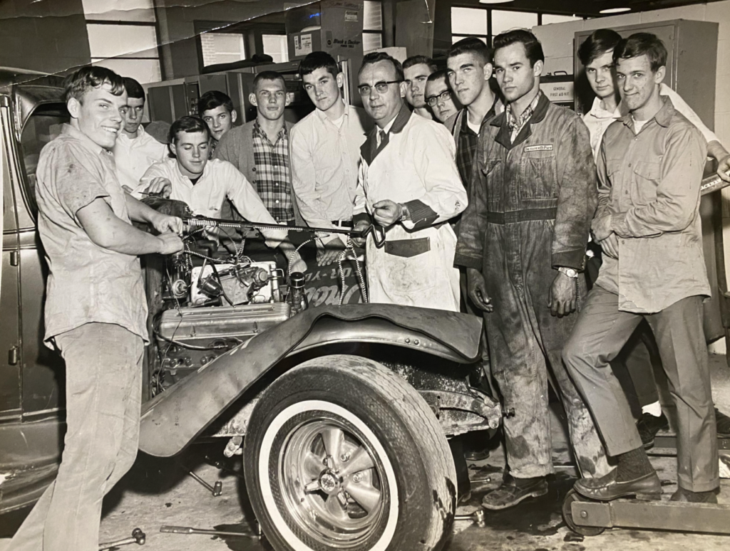 15. An auto mechanics teacher helping out his class, circa 1966
